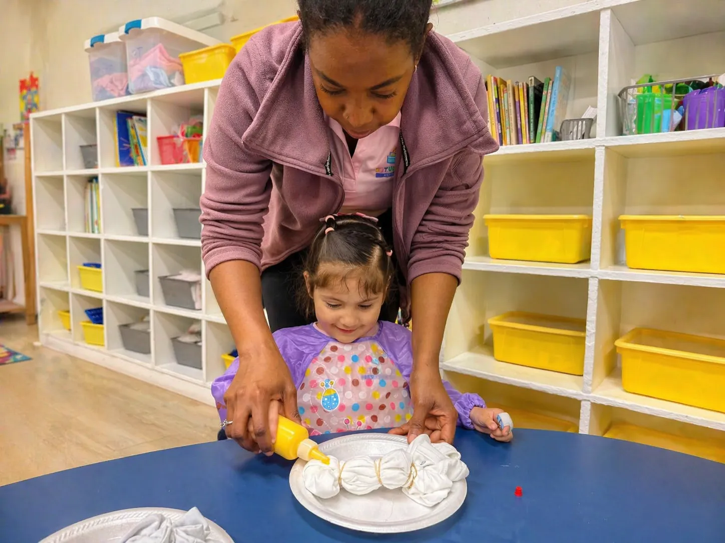 Teacher guiding a child in a warm, playful classroom